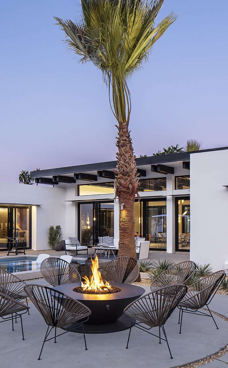 Modern white house with black trim and a pool and tall palm tree in the backyard