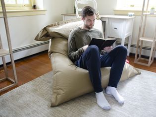 Person sitting in a Fatboy Original Bean Bag Chair and reading a book