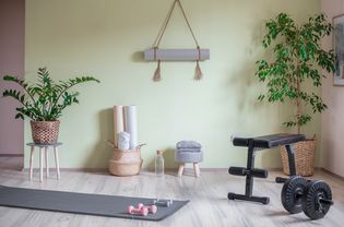 Light green-painted walls in workout room with yoga mats, hand weights and exercise bench