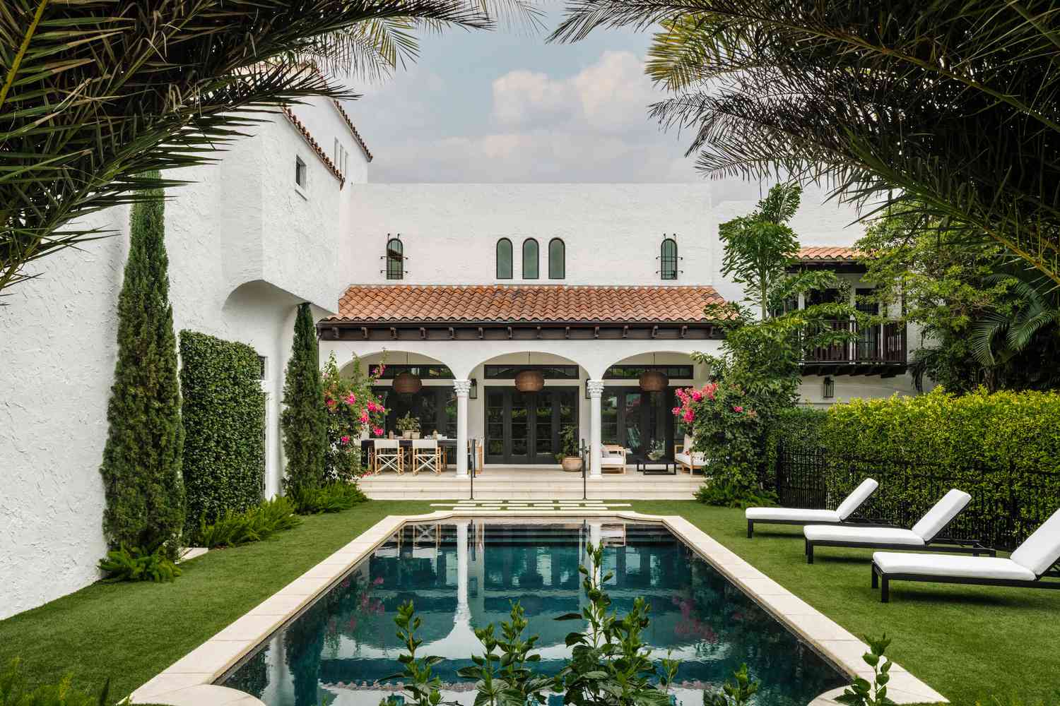 Backyard with pool and white house exterior with black trim and arched details
