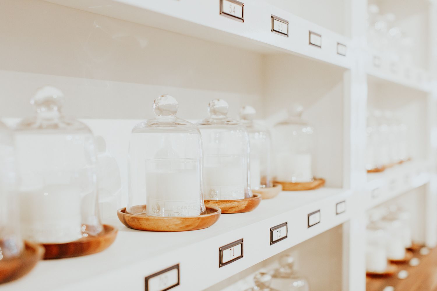 white candles with cloches on white shelves