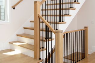White staircase with a wood and metal railing on wooden steps closeup