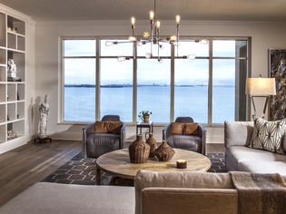 A neutral brown and gray living room with a view of water. The room follows the 60-30-10 rul