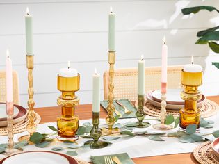 Closeup of a dining room table decorated with candles and colored glass candle holders