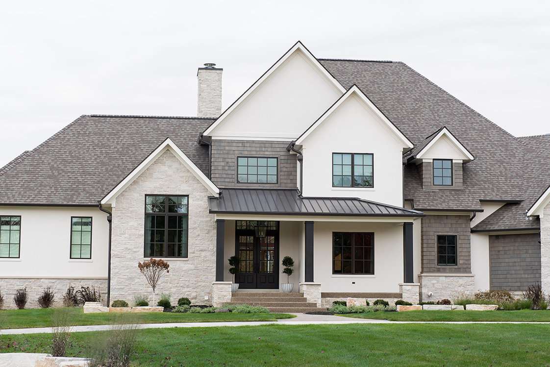 House with warm white exterior, black windows and pillars, shingle roof and stone accents