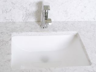 Water in a slow draining sink surrounded by white marble