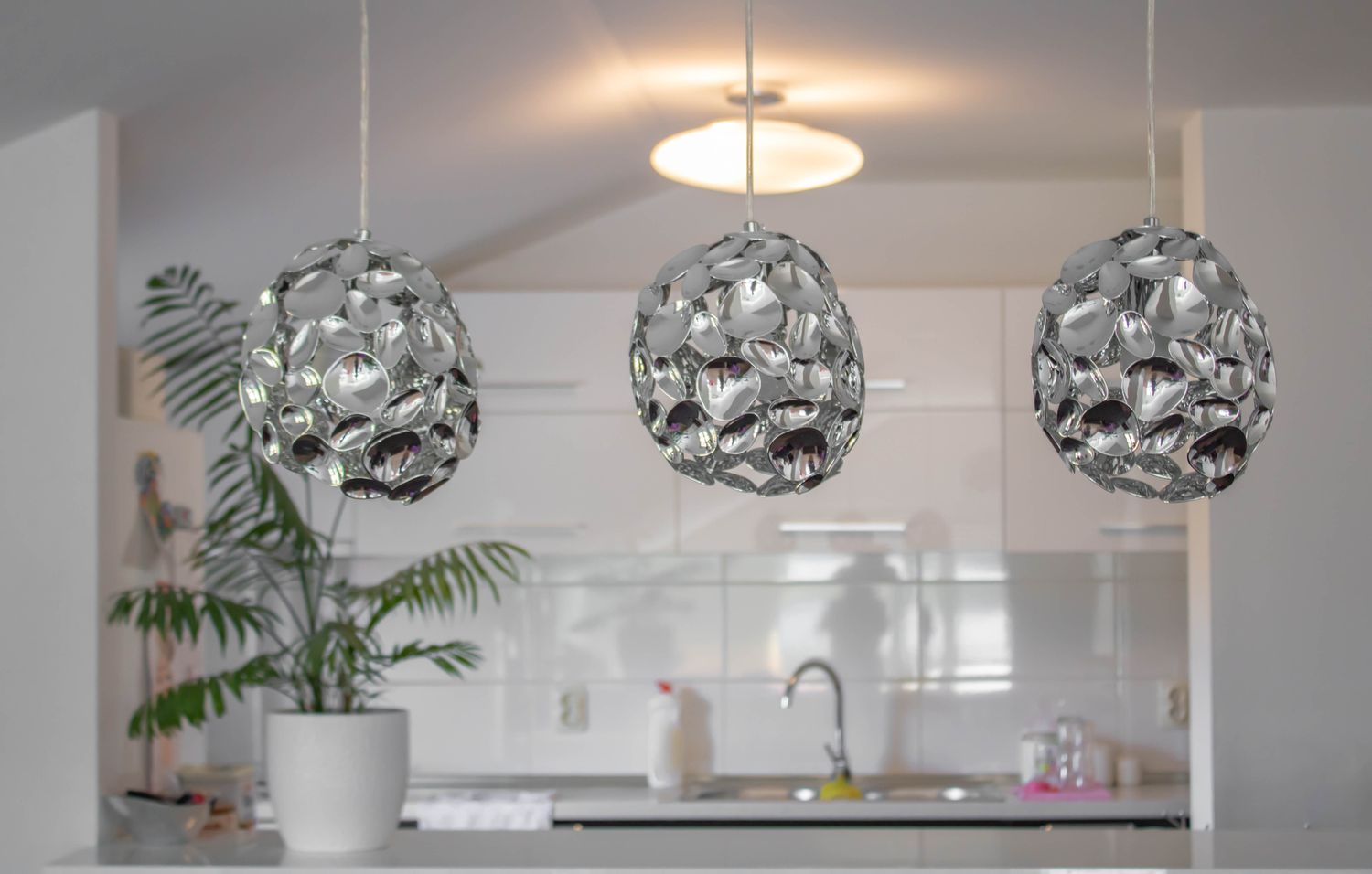 Three modern metallic pendant lighting hanging in front of kitchen