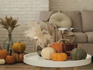 A living room decorated for fall with pumpkins and candles.
