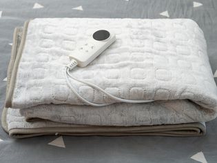 Folded heated electric blanket with controller on bed