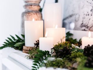 White pillar candles and greenery on a mantle