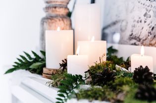 White pillar candles and greenery on a mantle