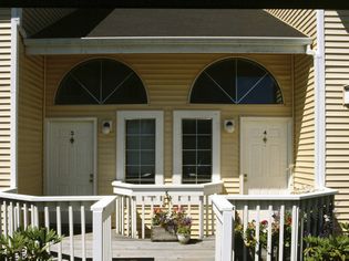 A duplex home with white doors and light yellow siding