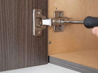 person adjusting a cabinet door
