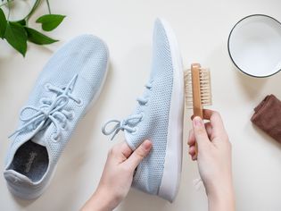 Light blue Allbirds sneakers being cleaned with bristled brush