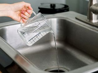 person using vinegar to unclog a sink