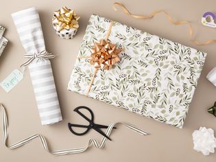 Professionally wrapped gift with foliage patterned wrapping paper next to materials