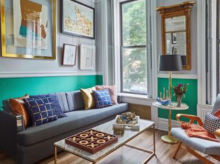 A bright and eclectic living room with teal walls and lots of artwork.