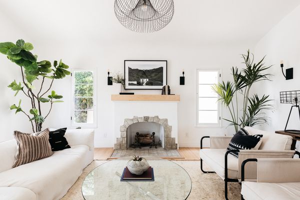 Living room with fireplace surrounded by white-themed decor and houseplants