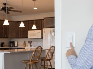 Light switch being pressed to turn off kitchen lights and lower electricity bill