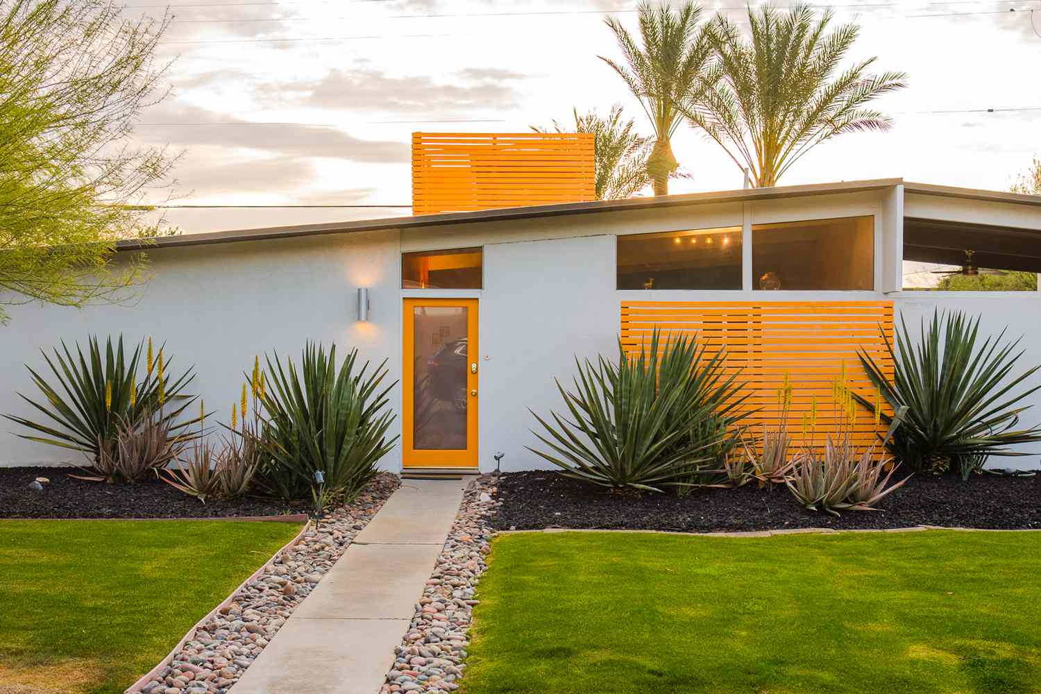 Yellow and white mid-century modern home with large plants in front