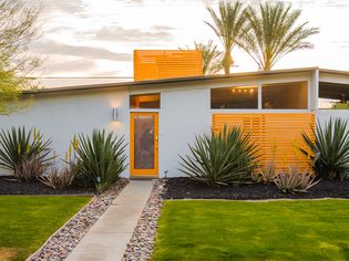 Yellow and white mid-century modern home with large plants in front