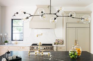 Modern kitchen with black marble-top island and Mid-century modern lighting above