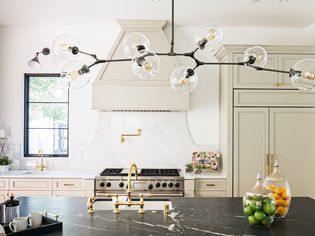 Modern kitchen with black marble-top island and Mid-century modern lighting above