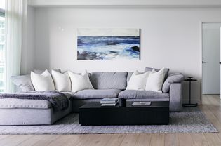 Light gray sectional couch with white cushions in minimalist-styled living room