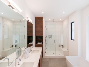 Modern bathroom with wood cabinet surrounded by white walls and countertops