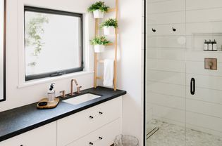 Modern farmhouse bathroom with black countertops and wooden decor items