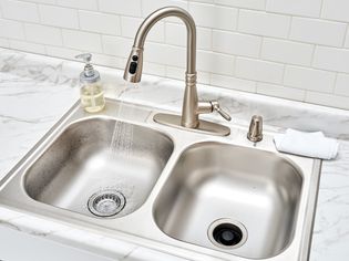 Surface-mounted double sink with running faucet water on marble countertop