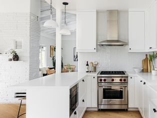 White-themed kitchen with stainless steel appliances open to living space