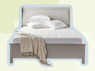 A gray bed with a cooling mattress pad, throw blanket, and pillows