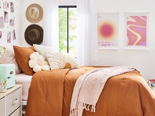 Fun dorm room with terracotta bedding and pink pillows.