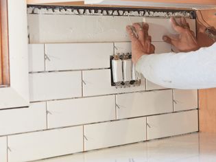 White tile backsplash being installed for kitchen remodeling