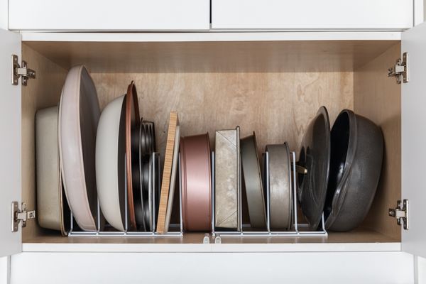Front view of pots and pans in an organizer inside of a kitchen cabinet