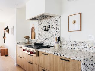 White, black and tan terrazzo tile installed as kitchen countertop and backsplash