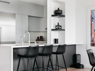Modern kitchen with light gray cabinets, stainless steel appliances and black furniture
