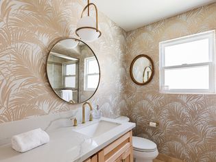 Bathroom covered with wallpaper of tan palm leaves