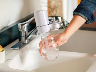Glass being filled with water from faucet with water filtration system