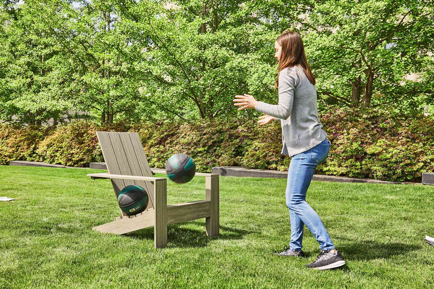 Person testing Adirondack chair durability by throwing balls at it