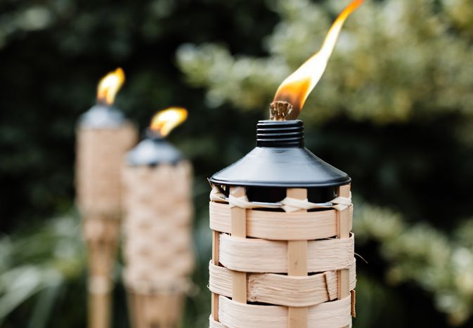 Citronella tiki torches with fire lit to keep mosquitos away closeup