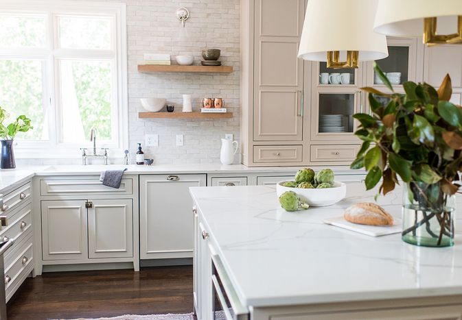 Bright white and beige kitchen with a large island and magnolia leaves in a vase.