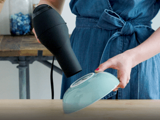 Woman pointing a hair dryer at the bottom of a bowl